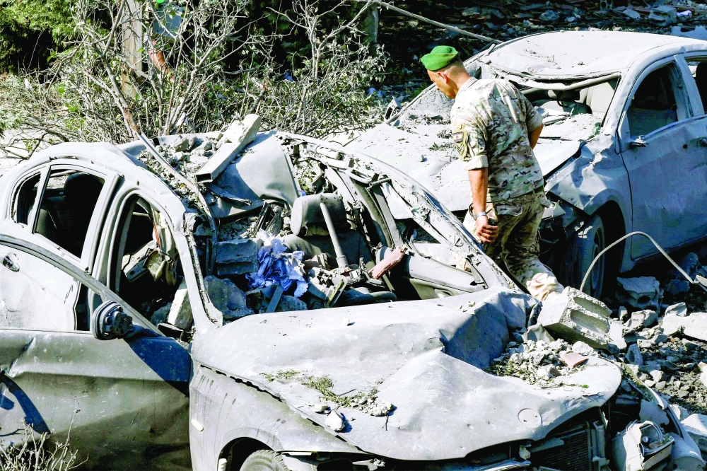 A Lebanese army soldier inspects destroyed vehicles at the site of an overnight Israeli airstrike on the village of Kfar Roummane. — AFP