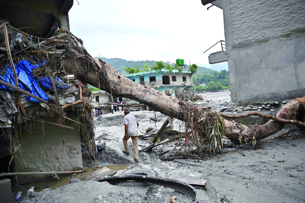A man walks past a damaged house in the aftermath of flash floods in Devighat, Nepal's Nuwakot district on September 5, 2026. So far, 1,344 bodies have been recovered in Nepal, according to the disaster agency, with around 5,000 people missing. (Photo by Pedro Pardo / AFP)
