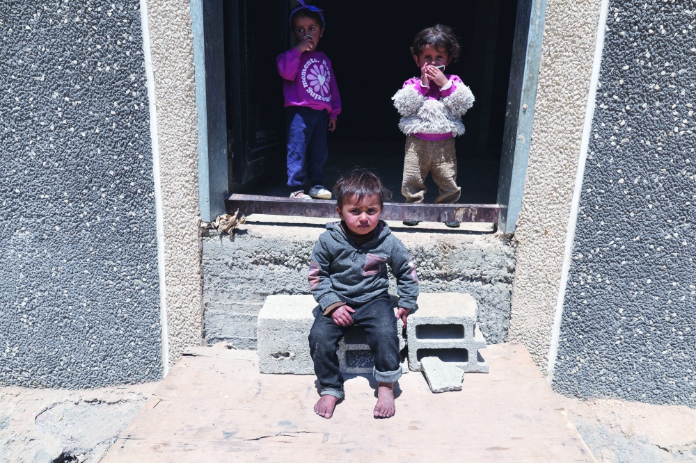 Children look on at the entrance to their home in the Palestinian village of Duma, near Nablus. — Reuters 