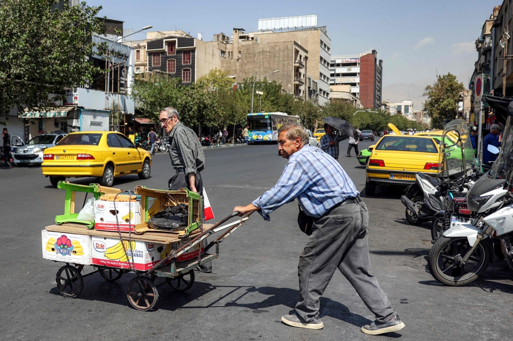 A vendor pushes a cart carrying his merchandise along a market street in Tehran on September 7, 2026