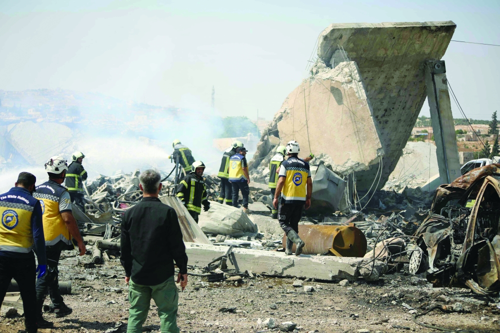 Syrian White Helmets rescuers inspect the damage at the site of an explosion in the town of Samarda in Idlib province. — AFP