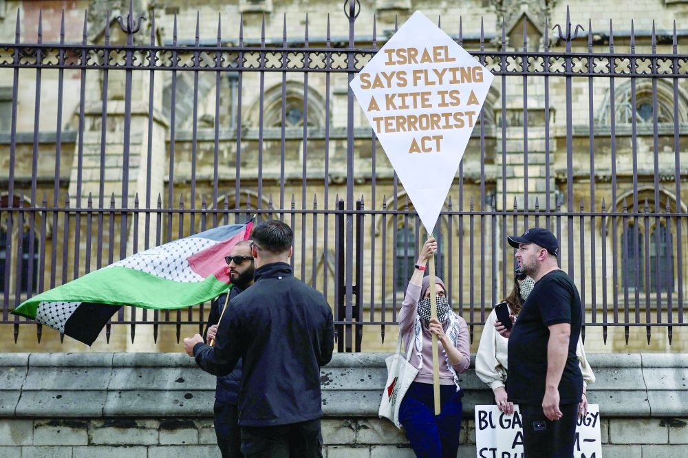 Protesters hold placards and a Palestinian flag outside the Houses of Parliament in central London. — AFP