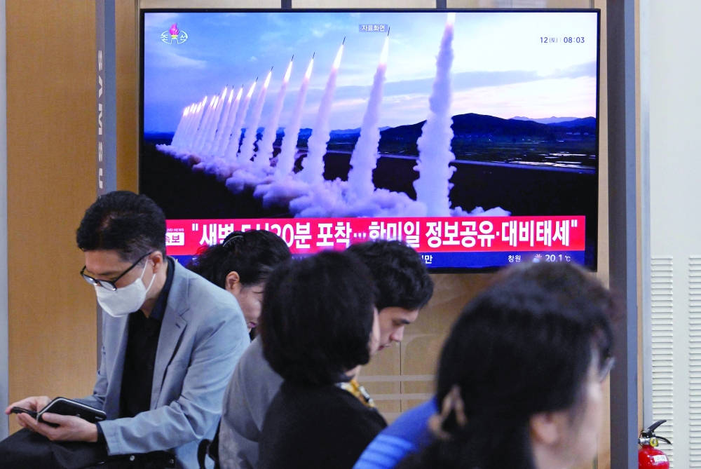 People sit near a TV screen showing a news broadcast with file footage of a North Korean missile test, at a train station in Seoul. — AFP