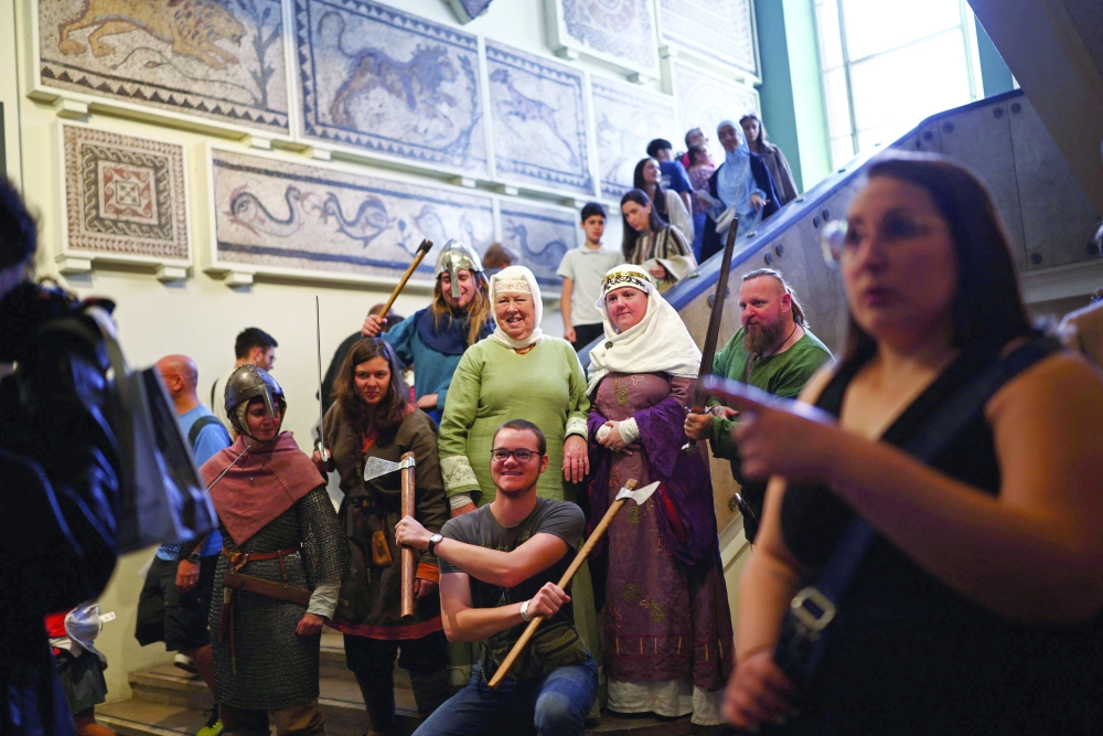 Staff in period costume poses with visitors inside the British Museum in London — AFP