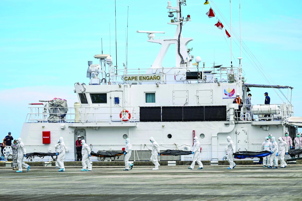 Philippine Coast Guard personnel in protective suits carry victims from the ferry fire to a tent for identification at the port of Borac in Coron, Palawan province. - AFP