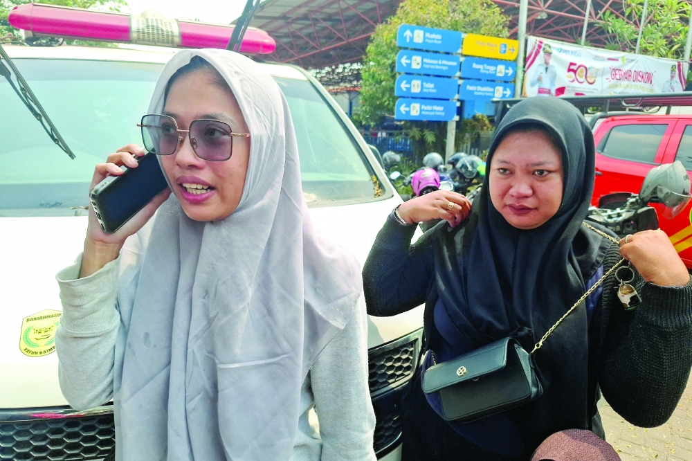 Relatives of passengers aboard the Virgo Transport 8 ship that, according to a search and rescue agency, sank while sailing from Surabaya in East Java to Banjarmasin in South Kalimantan, speak on a phone while waiting for news about the search and rescue operation, at Trisakti port in Banjarmasin, South Kalimantan province, Indonesia, September 13, 2026. REUTERS/Stringer
