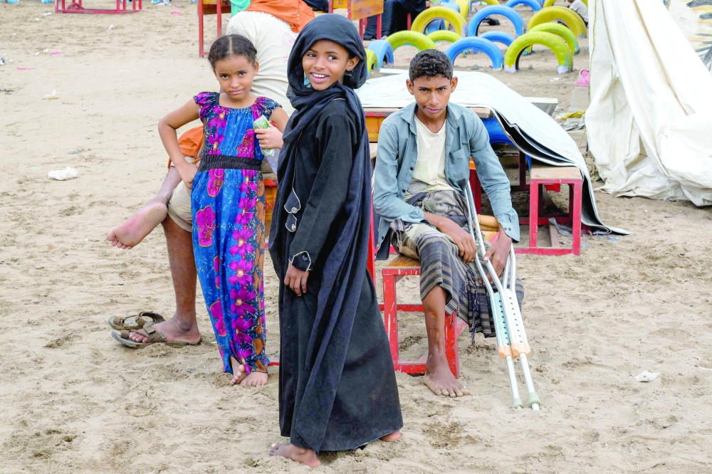A girl, standing next to another girl and a boy with crutches, looks on at a temporary shelter for internally displaced people (IDPs) at the Shawkani school, north of Aden in southern Yemen, on Tuesday. The fighting in Yemen in recent weeks has displaced nearly 86,000 people, a UN agency said on September 13, with the number surging by 10,000 from a day earlier. — AFP