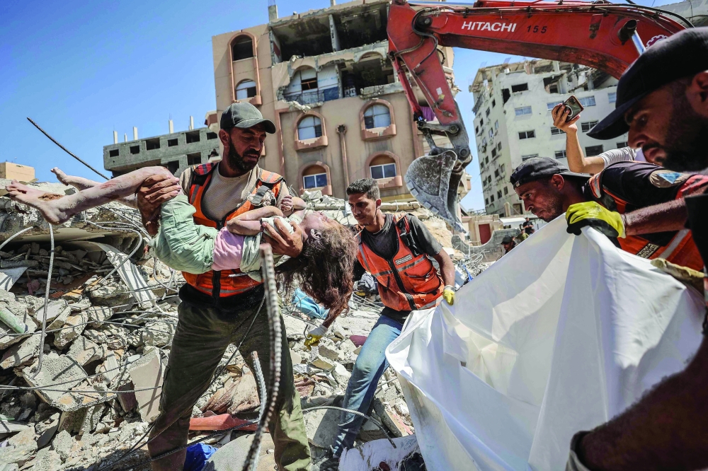 A rescuer carries the body of a Palestinian girl at the site of a collapsed building in the Tal al-Hawa area of Gaza City on Wednesday. — AFP