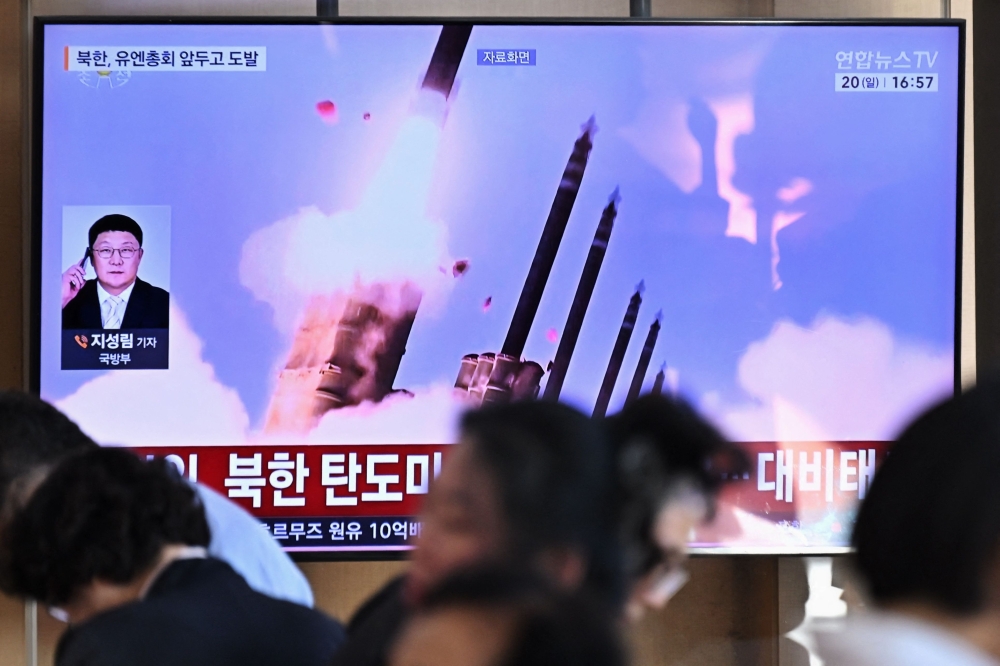 People sit near a television screen showing a news broadcast with file footage of a North Korean missile test, at a train station in Seoul on September 20, 2026.