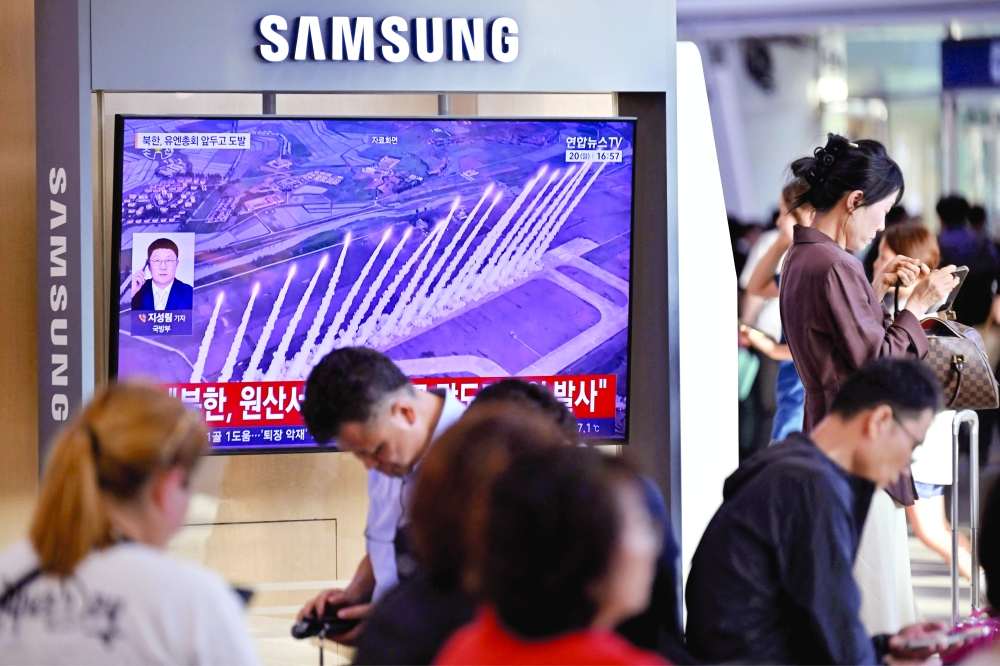 People sit near a television screen showing footage of a North Korean missile test at a train station in Seoul. — AFP