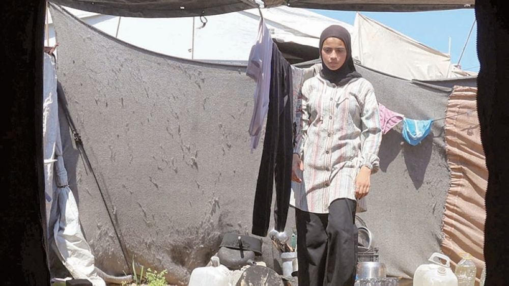 Displaced Palestinian stands next to drying laundry at a tent camp in Khan Younis. — Reuters