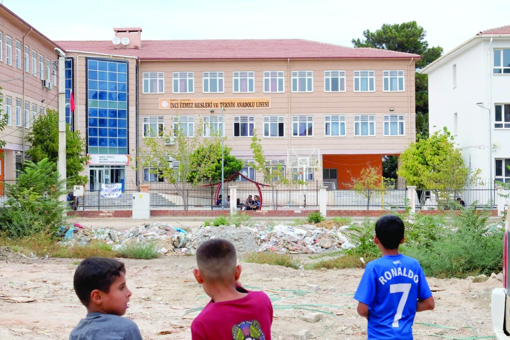 Children look at a high school where a gunman opened fire wounding eleven people and was detained shortly afterwards, in Turgutlu, an area west of the resort city of Izmir, on September 22, 2026.  A teenager opened fire outside a high school in western Türkiye on September 22, wounding 11 people before being detained by police, a minister said. The incident happened around 8:00 am (0500 GMT) in Turgutlu in Manisa province, near the western resort city of Izmir, the regional governor's office said.  (Photo by Ilker ERAY / AFP)