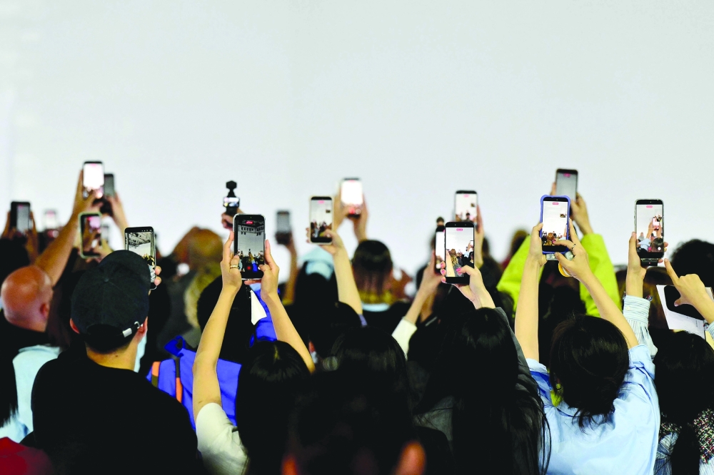 Guests hold their smartphones during the Prada collection show as part of Women's Spring/Summer 2027 Milan's fashion week. -AFP 
