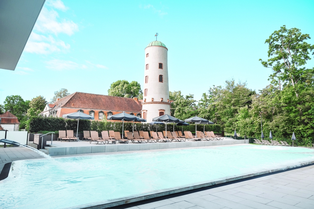 Waitzscher Turm and a crystal-clear outdoor pool, water jets, and wooden lounge chairs.
