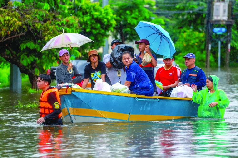 People ride in a boat along a flooded street during heavy rain in Bangkok, Thailand, September 26, 2026. 
