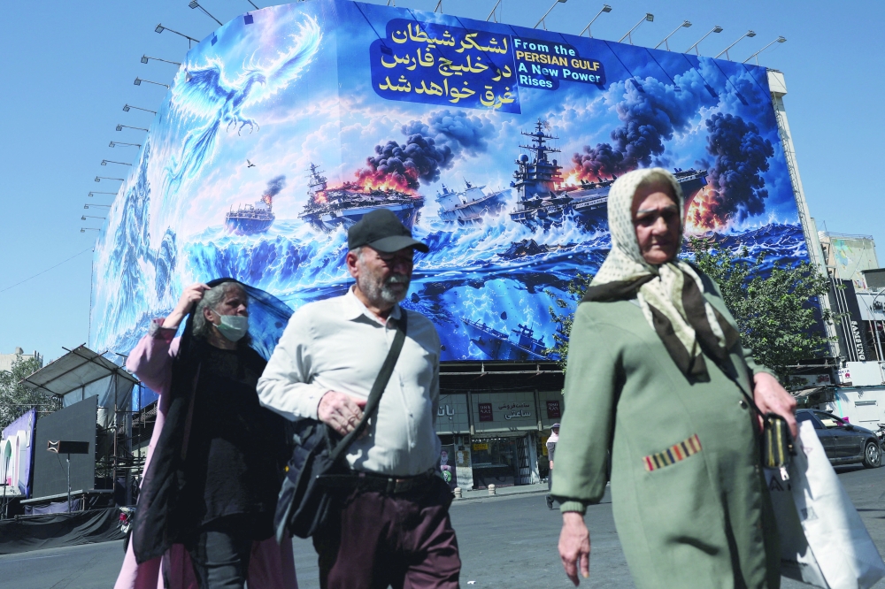 People walk past a billboard about the Strait of Hormuz, on a building in Tehran. — Reuters 
