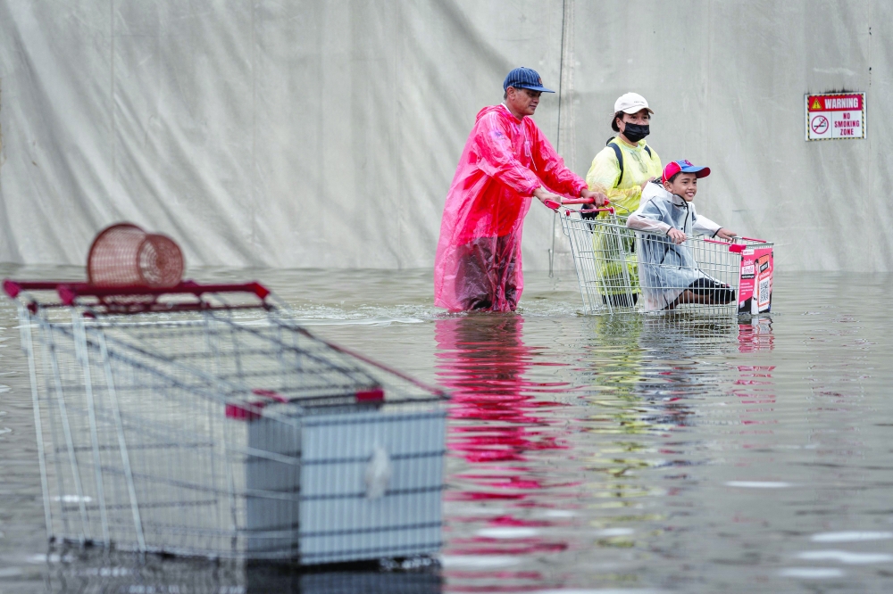 A family makes their way with a cart through floodwaters in the Bang Kapi district of Bangkok. — AFP