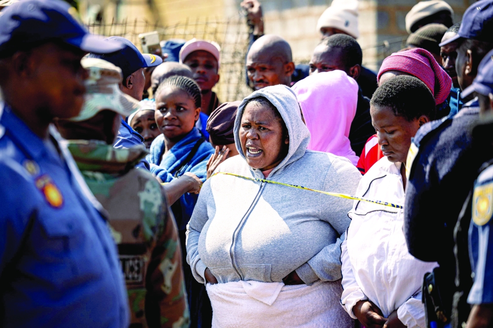 Residents gather behind police tape near the scene where gunmen armed with assault rifles stormed. —AFP