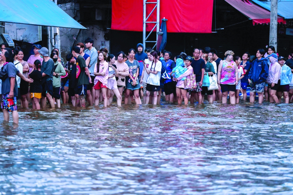 People queue for food in a flooded area following heavy rain. — AFP