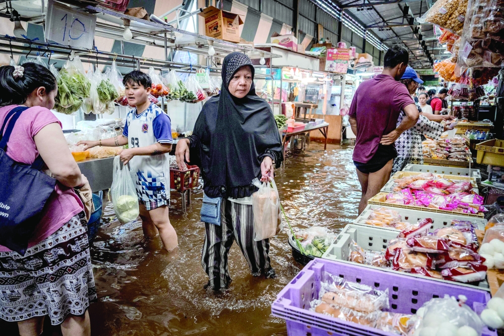 People visit a flooded fresh food market in the Bang Kapi district of Bangkok. — AFP