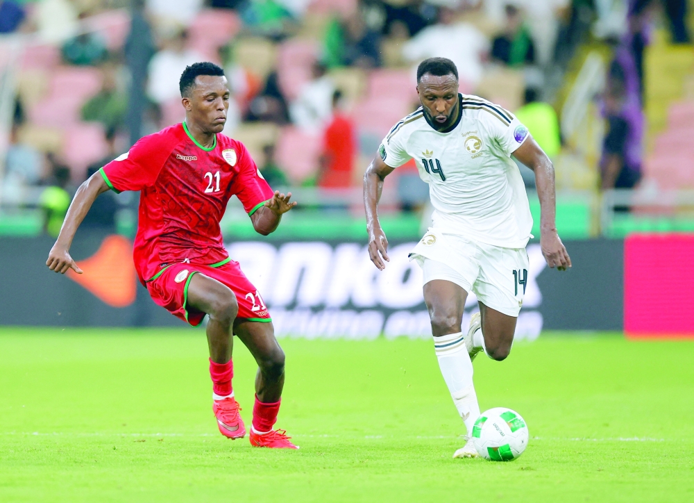 Saudi Arabia's Hassan Kadesh in action with Oman's Sultan al Marzouqi at King Abdullah Sport City Stadium. — Reuters