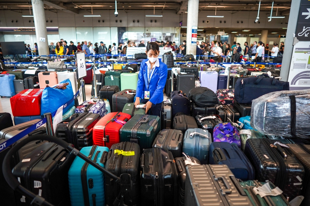 An airport officer arranges baggage from Thai Airways flights at Suvarnabhumi International Airport, after heavy rain and flooding disrupted the airline's ground operations, in Bangkok