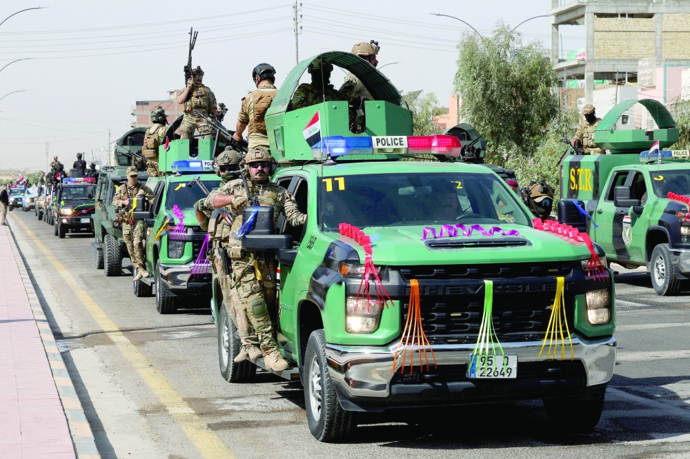 Members of the Iraqi security forces drive in a convoy in Najaf, Iraq. — Reuters