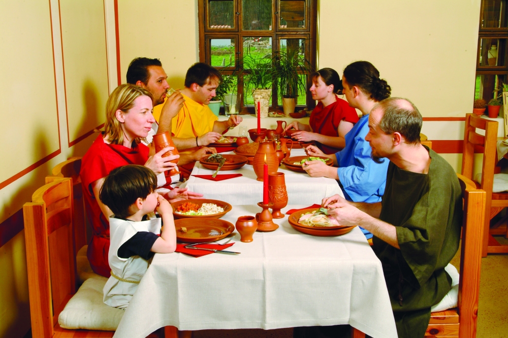 A traditional meal at Roman Villa Borg Archaeological Park — guests in period clothing enjoying authentic flavours by candlelight.