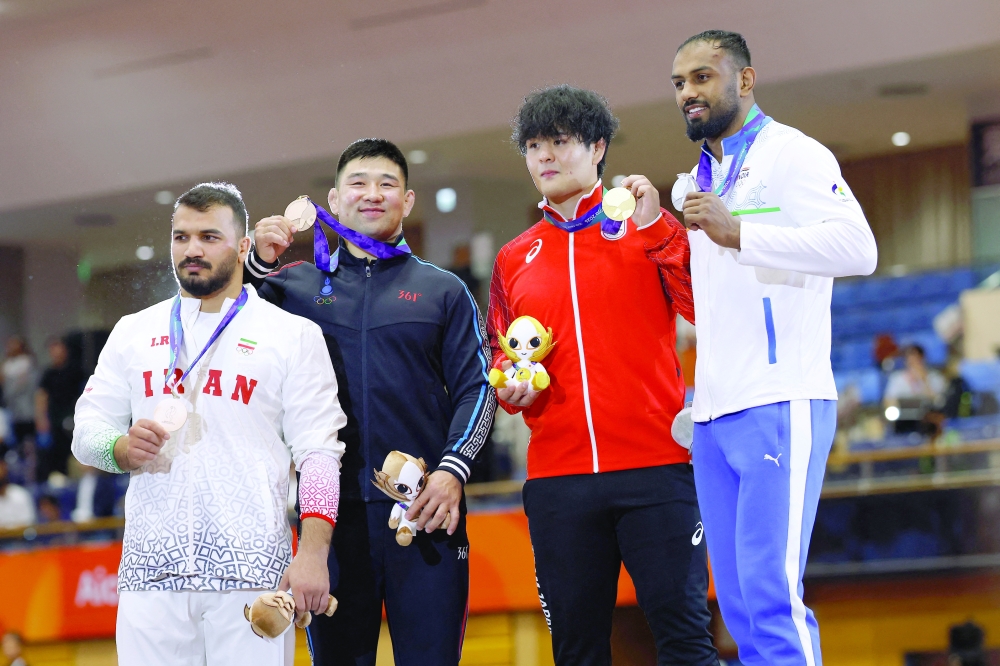 Gold medallist Japan's Yuri Nakazato celebrates on the podium after winning the men's greco-roman 97kg with silver medallist India's Nitesh and bronze medallists Iran's Mehdi Balihamzehdeh and Mongolia's Gankhuyag Ganbaatar. — Reuters