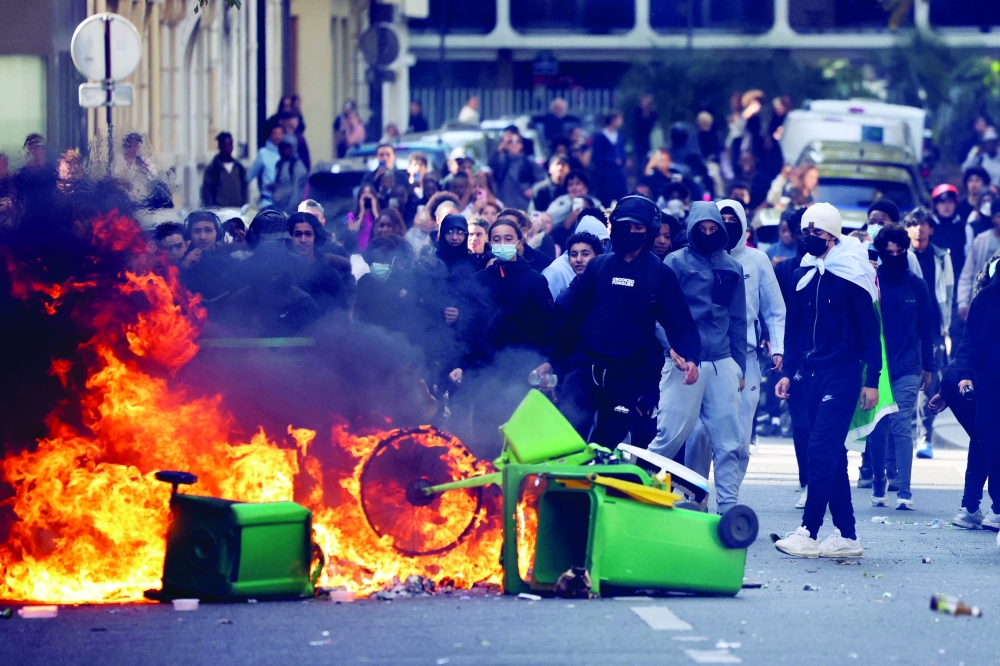 A student puts trashes into a fire as protesting students carry out blockading action near place de la Nation in Paris. — AFP