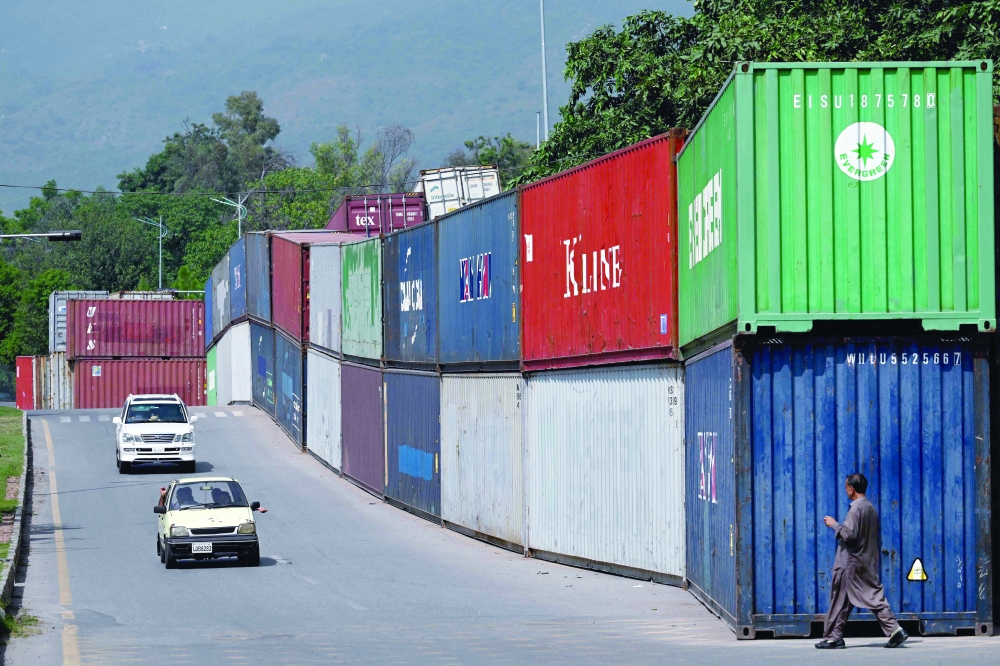 Commuters drive past shipping containers placed by authorities to block access to the Red Zone in Islamabad, Pakistan, on Sunday, ahead of a protest by supporters of former prime minister Imran Khan. — AFP