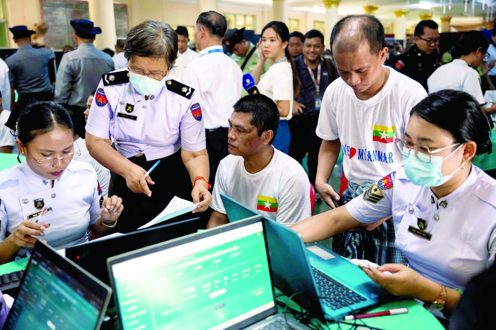 Immigration officers process the documentation of Myanmar migrants repatriated from Malaysia in Thanlyin, near Yangon, on Sunday. — AFP