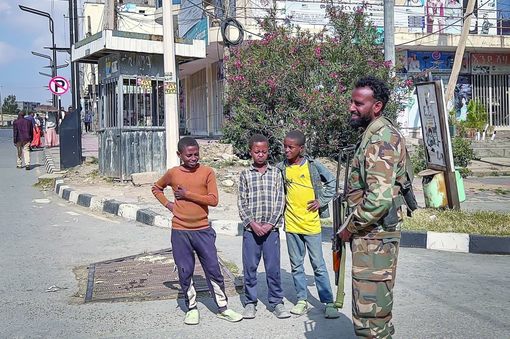 Young residents watch a member of the pro-government Tigray Peace Force patrol the streets as federal and allied forces enter Mekelle, the capital of Ethiopia's Tigray region, on Sunday. — AFP