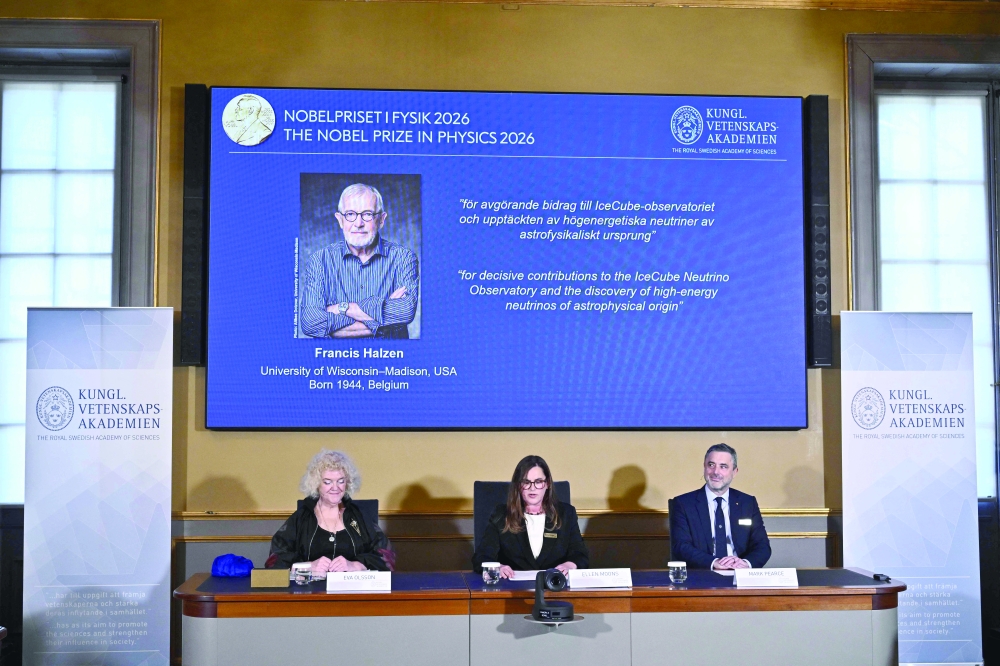 Eva Olsson, Ellen Moons, and Mark Pearce sit in front of a screen displaying Francis Halzen as the recipient of the 2026 Nobel Prize in Physics at the Royal Swedish Academy of Sciences in Stockholm. — AFP