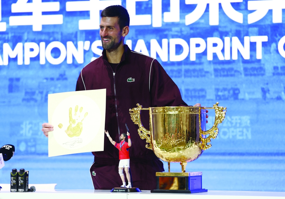 Serbia's Novak Djokovic poses with a print of his hand, a mini figure of himself and the trophy during a press conference after winning the China Open final against Australia's Alex de Minaur. — Reuters