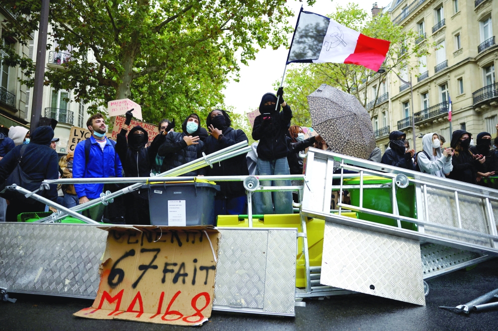 A protester holds a French flag behind a barricade to block the Boulevard Saint-Germain in Paris. — Reuters