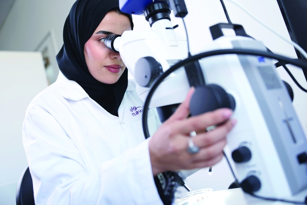 A researcher examines a sample under a microscope; the conference will focus on environmental microbiology and its applications. — ONA