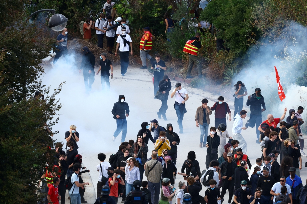 Protesters walk through tear gas amid clashes at Place de la Nation during a demonstration by high school and university students, supported by teachers' union and school parents