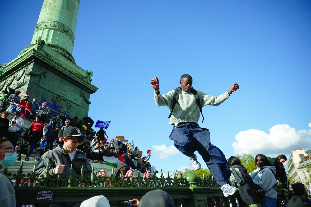 A protester jumps over a fence at Place de la Bastille in Paris on Thursday, during nationwide protests demanding better school conditions. — Reuters