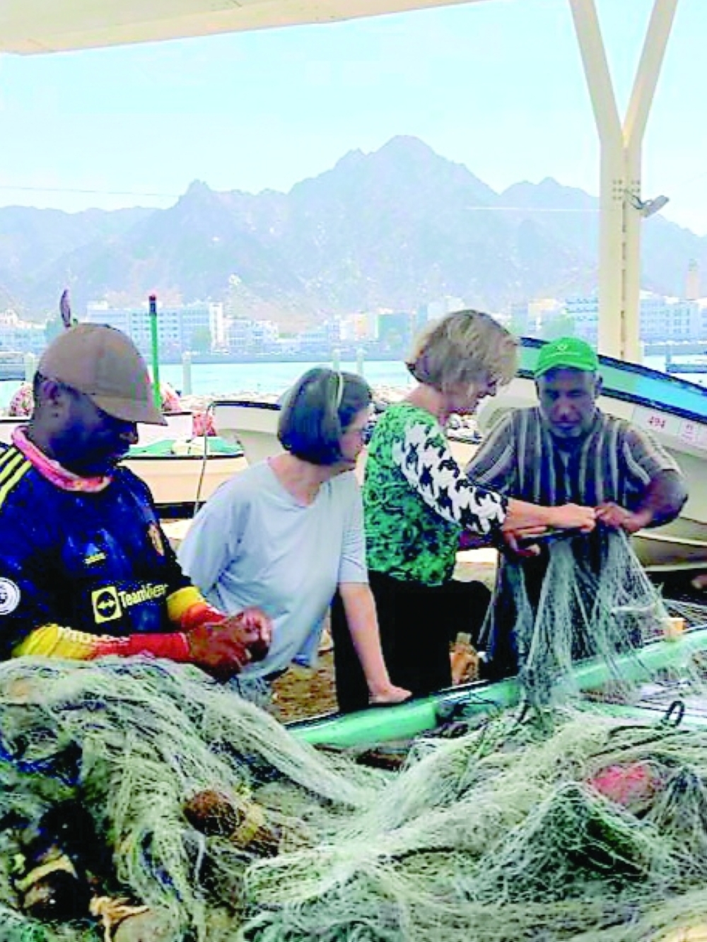 Fishermen of Muttrah with Barbara and Monika getting a lesson in traditional net work