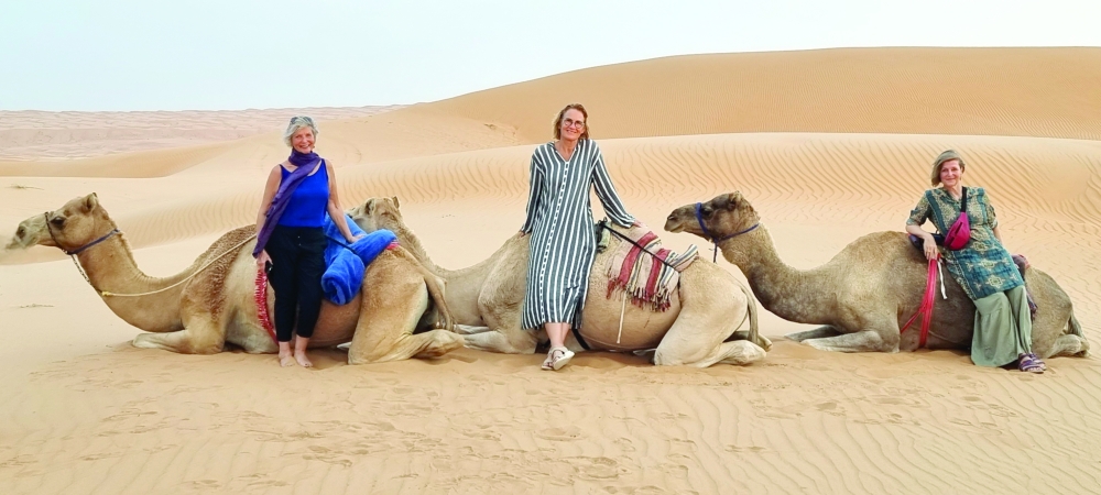 Monika Sommer (centre) and friends pose with camels in the desert dunes