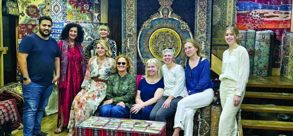 Women visitors pose with a local shopkeeper amidst colourful carpets at Muttrah Souq