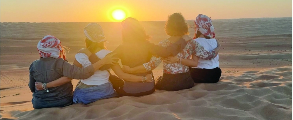 Women visitors share a sunset moment on the dunes in Oman’s desert