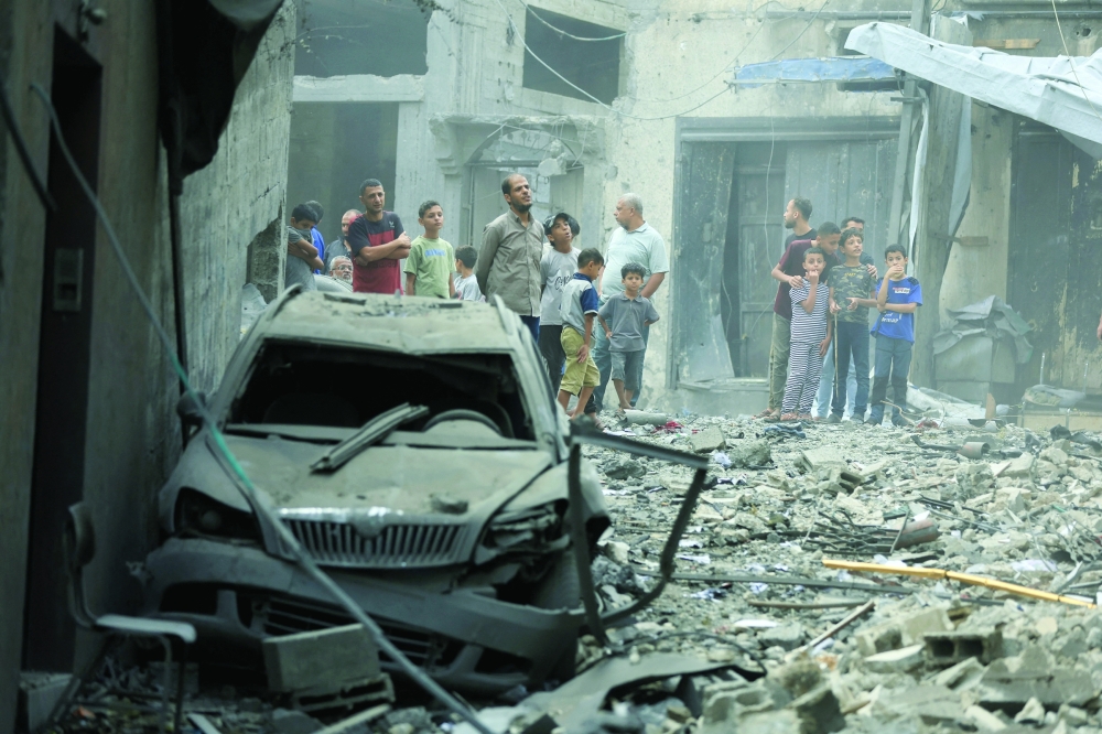 Palestinians inspect the site of a house targeted by Israeli airstrikes after the Israeli military warned residents to evacuate in Gaza City. — Reuters
