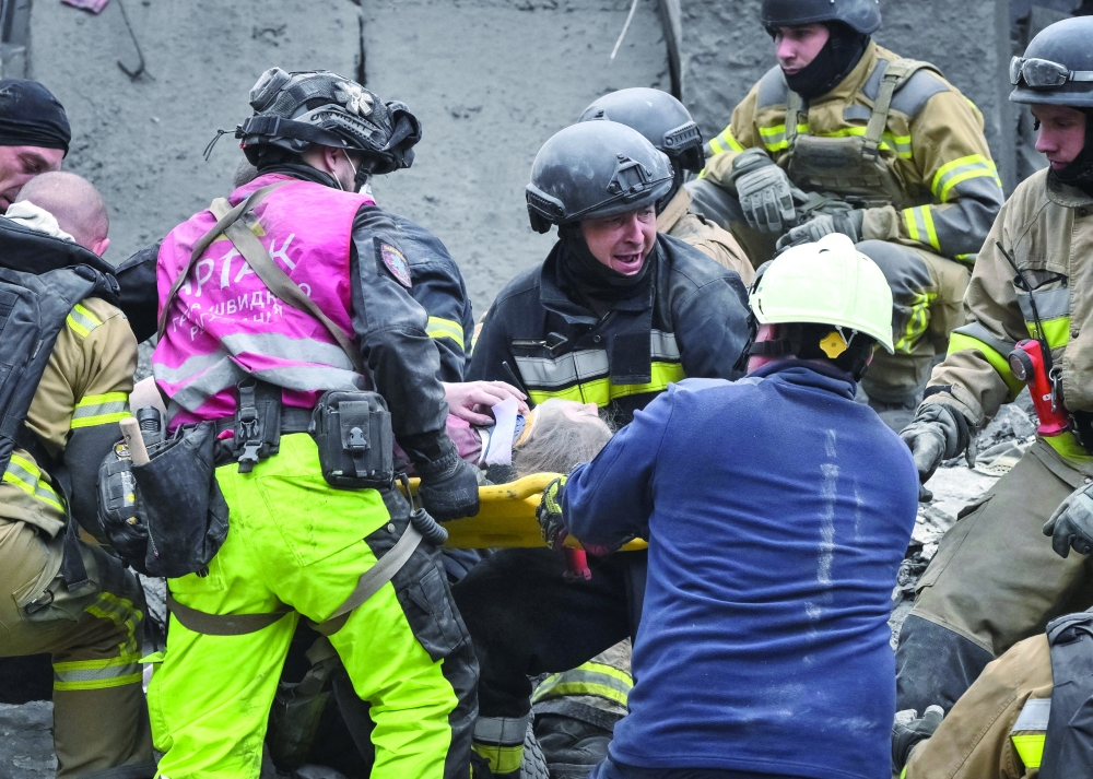 Rescuers evacuate a wounded woman found under debris damaged during a Russian air strike in Zaporizhzhia, Ukraine. — Reuters 
