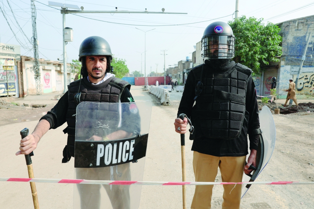 Members of the police stand guard near shipping containers blocking a road leading to the Red Zone in Peshawar. — Reuters