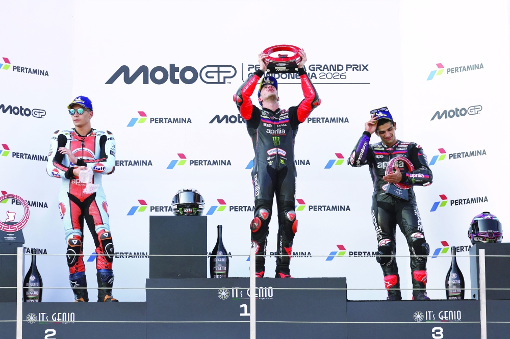 Aprilia Racing's Marco Bezzecchi celebrates on the podium with a trophy after winning the MotoGP race with second place Trackhouse MotoGP Team's Raul Fernandez and third place Aprilia Racing's Jorge Martin. — Reuters