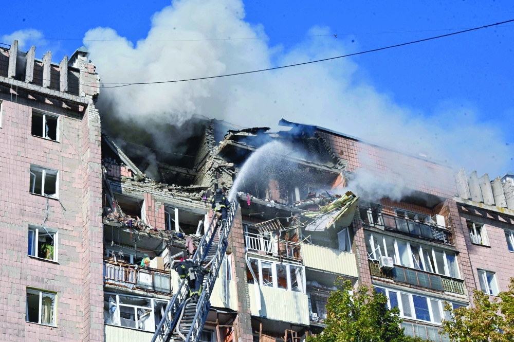 Firefighters work at a residential building damaged in a Russian drone strike in Kharkiv. — AFP