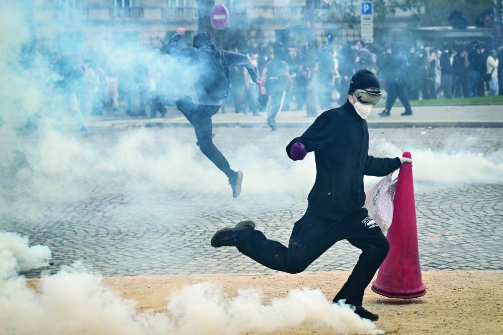 A protester kicks back a tear gas canister during a demonstration of high-school students in Paris. — AFP 
