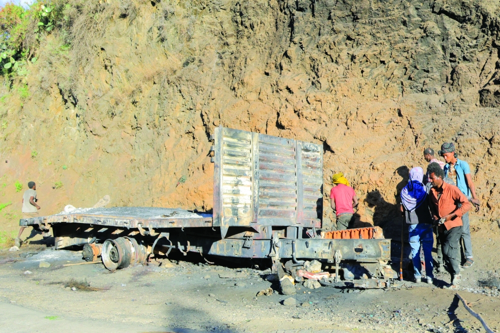 People disassemble an abandoned wreckage of a truck during fighting in Adi Mesno, Ethiopia. — Reuters